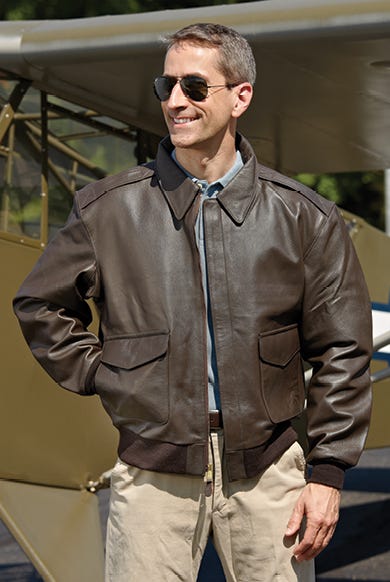 Pilot standing in front of plane wearing aviation leather jacket