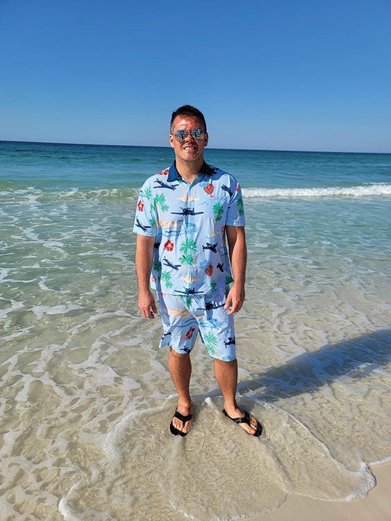 beach and ocean model with aviation themed shirt and swim trunks