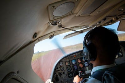 A pilot wearing an aviation headset looking out the window from inside the cockpits