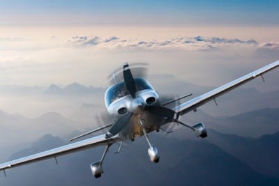 A small airplane flying directly toward a wall of dark, heavy clouds