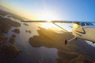 Two small airplanes flying in close formation against a partly cloudy sky